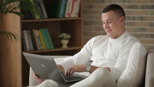 Man sitter på soffan med laptop — Stockvideo