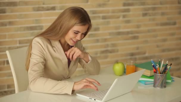 Дівчина сидить за столом за допомогою ноутбука — стокове відео