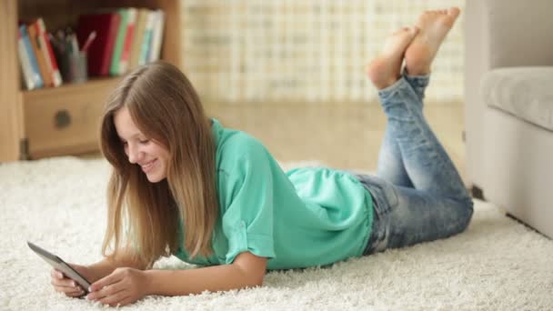 Gadis ceria berbaring di lantai menggunakan touchpad — Stok Video