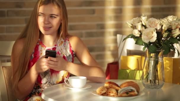 Girl sitting at cafe using mobile phone — Stock Video