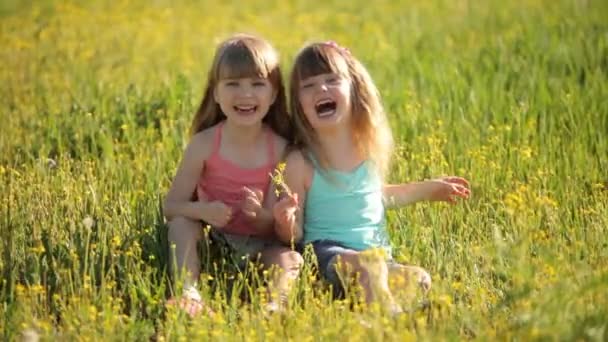 Twee kleine meisjes zitten op gras — Stockvideo