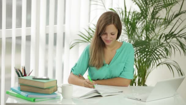 Meisje zit aan Bureau schrijven in notitieblok — Stockvideo