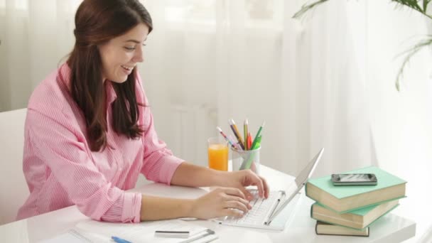 Dívka sedí u stolu pomocí přenosného počítače — Stock video
