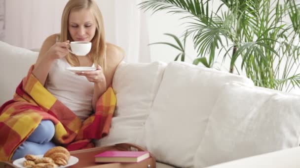 Frau entspannt sich auf Sofa und trinkt Tee — Stockvideo