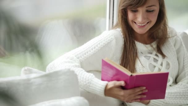 Dziewczyna siedzi przez okno czytania — Wideo stockowe