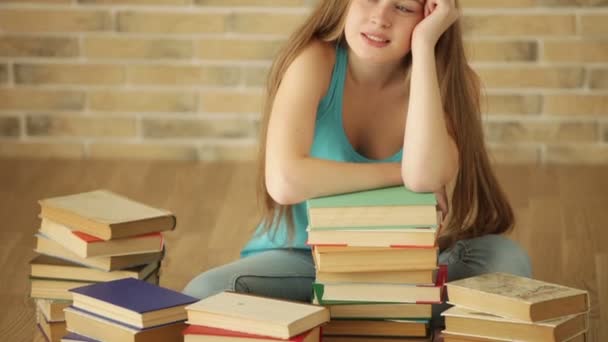 Glückliches Mädchen, das mit Büchern auf dem Boden sitzt — Stockvideo