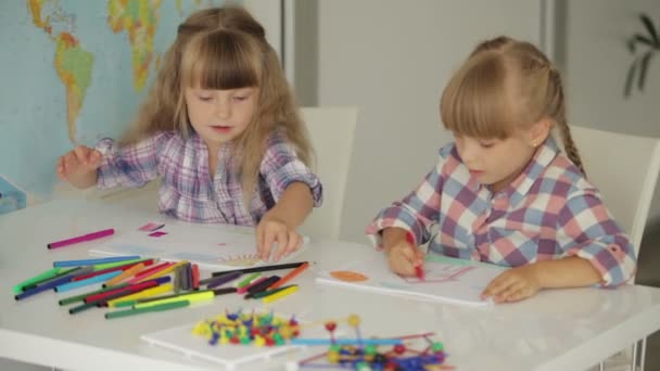 Twee kleine meisjes zitten op tabel tekenen — Stockvideo