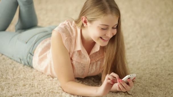 Fille sur le tapis en utilisant un téléphone mobile — Video