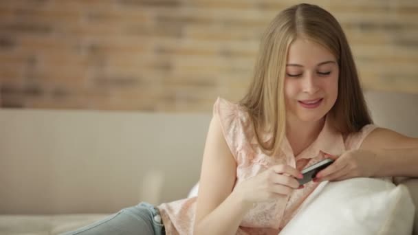 Κορίτσι στον καναπέ χρησιμοποιώντας το κινητό τηλέφωνο — Αρχείο Βίντεο