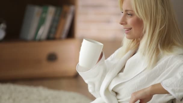 Жінка в халаті п'є з чашки — стокове відео