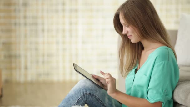 Wesoła dziewczyna siedzi na podłodze przy użyciu touchpad — Wideo stockowe