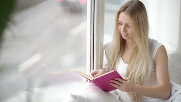 Κορίτσι που κάθεται από το παράθυρο ανάγνωσης — Αρχείο Βίντεο