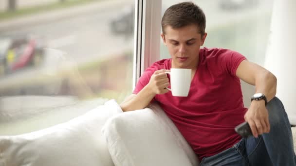 Мужчина пьет чай разговаривая по мобильному телефону — стоковое видео