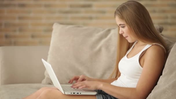 Menina sentada no sofá usando laptop — Vídeo de Stock