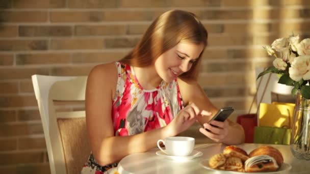 Girl sitting at cafe using mobile phone — Stock Video