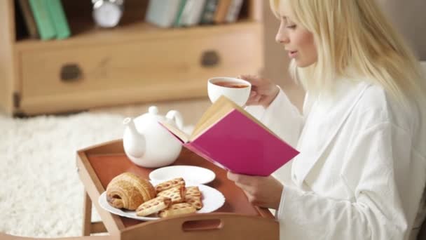 Женщина пьет чай чтение книги — стоковое видео