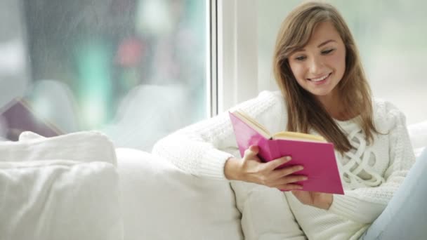 Lány ül a könyv olvasó ablakban — Stock videók