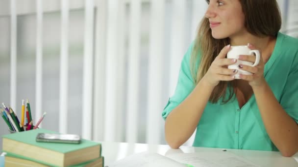 Chica encantadora sentada en el escritorio bebiendo — Vídeo de stock