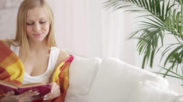 Woman relaxing on couch reading book — Stock Video