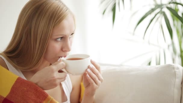 Menina sentada no sofá bebendo chá — Vídeo de Stock