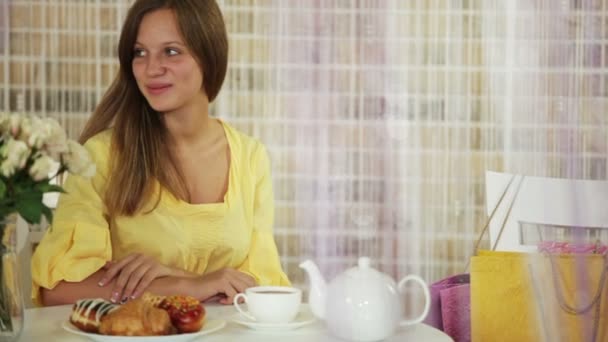 Hermosa chica sentada en la cafetería con una taza de té — Vídeo de stock