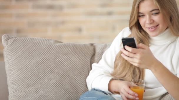 Menina sentada no sofá usando telefone celular — Vídeo de Stock