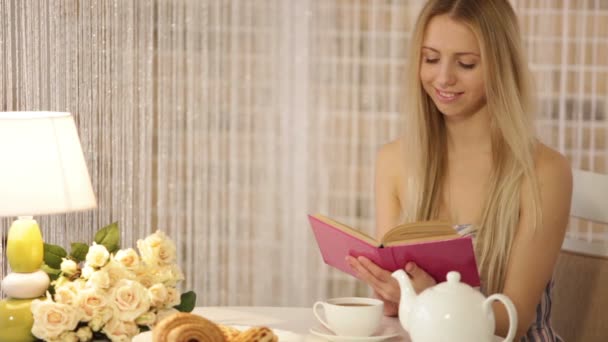 Дівчина сидить у кафе читаючи книгу — стокове відео