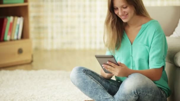 Touchpad kullanarak halı üzerinde oturan sevimli kız — Stok video