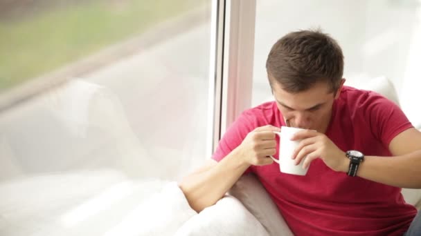 Άνδρας καθιστός παράθυρο κρατώντας φλιτζάνι τσάι — Αρχείο Βίντεο