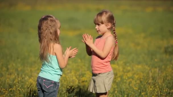 Två små flickor klappa händerna i blommor. — Stockvideo