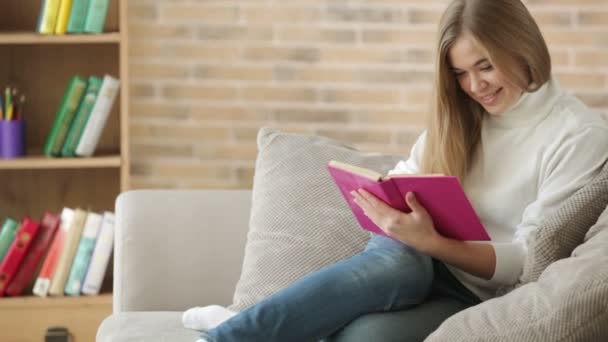 Ragazza sveglia seduta sul divano lettura libro — Video Stock