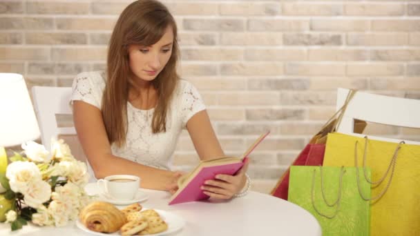 Mädchen sitzt im Café und liest Buch — Stockvideo