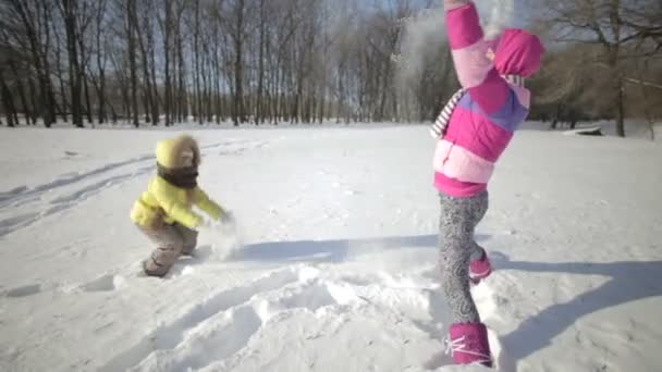 Moeder en baby gooien sneeuw. — Stockvideo