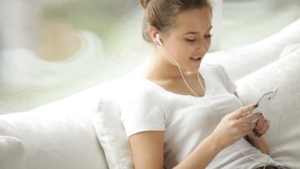 Menina usando fones de ouvido usando telefone celular — Vídeo de Stock