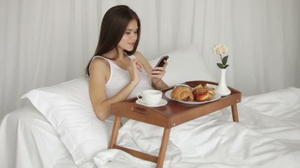 Fille au lit en utilisant un téléphone mobile — Video