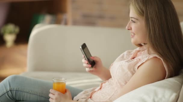 Menina usando telefone celular beber suco — Vídeo de Stock