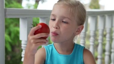 Küçük kız büyük bir kırmızı tomat yeme