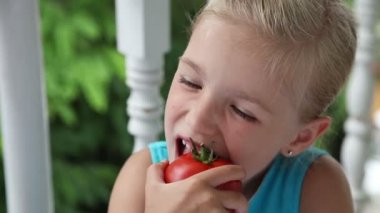 Küçük kız büyük bir kırmızı domates yeme