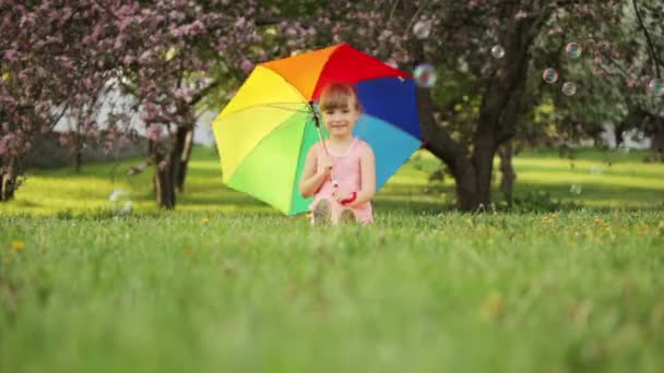 Mała dziewczynka siedzi w ogrodzie — Wideo stockowe