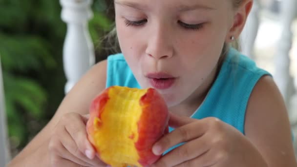 Little girl eating a big peach