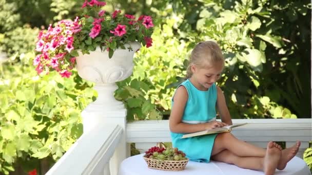Девушка читает книгу в саду . — стоковое видео