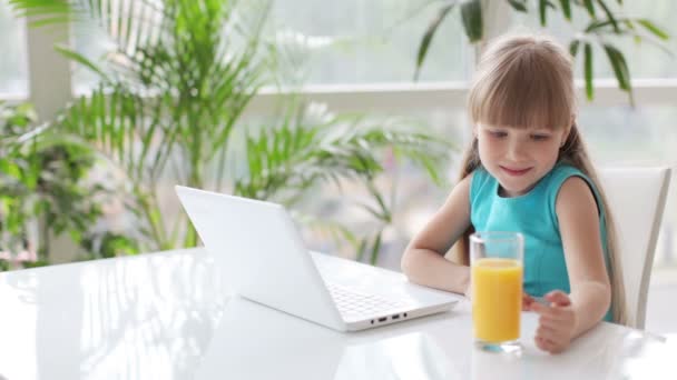 Linda niña usando el ordenador portátil y sonriendo . — Vídeos de Stock