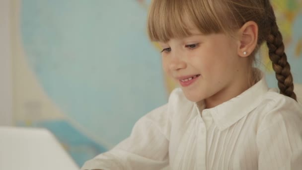 Meisje zit aan bureau met behulp van laptop — Stockvideo