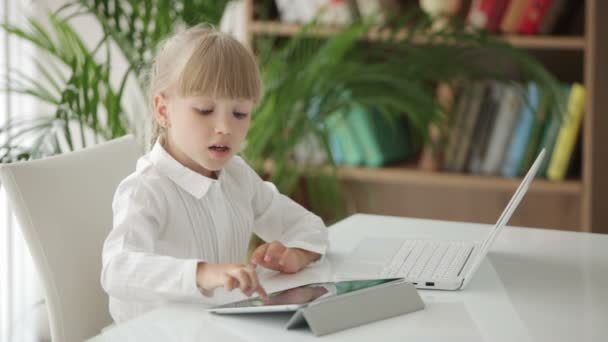 Meisje zit aan tafel met laptop — Stockvideo