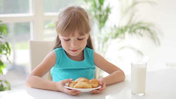 Забавная маленькая девочка сидит за кухонным столом — стоковое видео