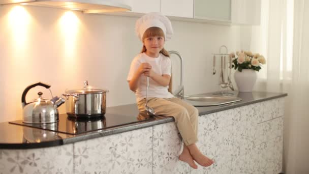 Chica sentada en la mesa de la cocina — Vídeo de stock