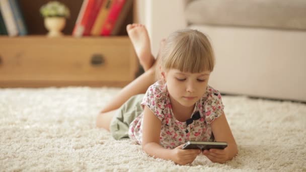 Κορίτσι ξαπλωμένο στο πάτωμα με το κινητό τηλέφωνο — Αρχείο Βίντεο