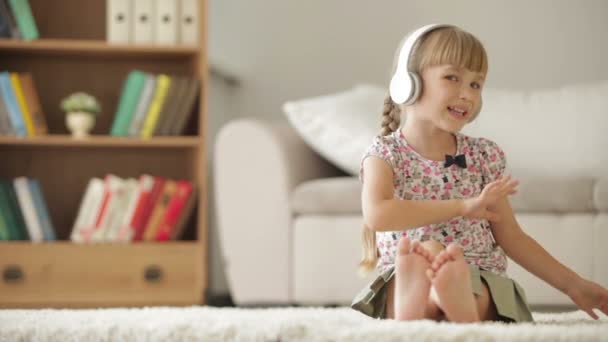 Legrační malá holčička v sluchátka sedět — Stock video