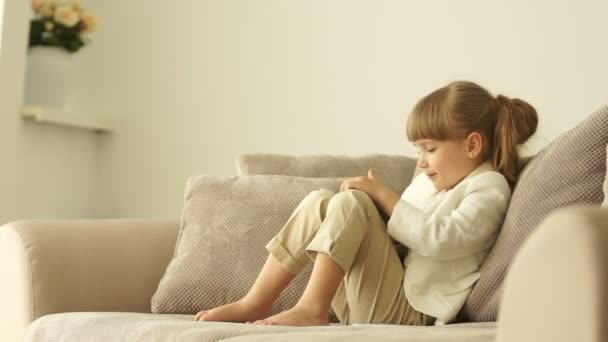 Niedliches kleines Mädchen sitzt auf dem Sofa — Stockvideo