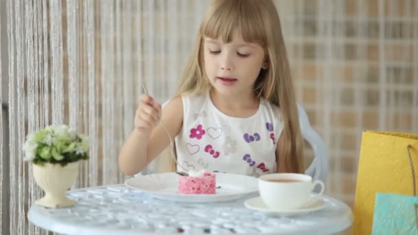 Девушка сидит за столом и ест торт — стоковое видео